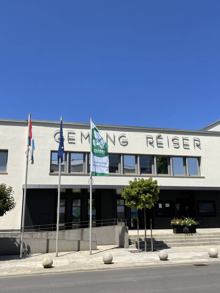 Die mayors-for-Peace-Flagge vor einem Gebäude in Roeser (Luxemburg)